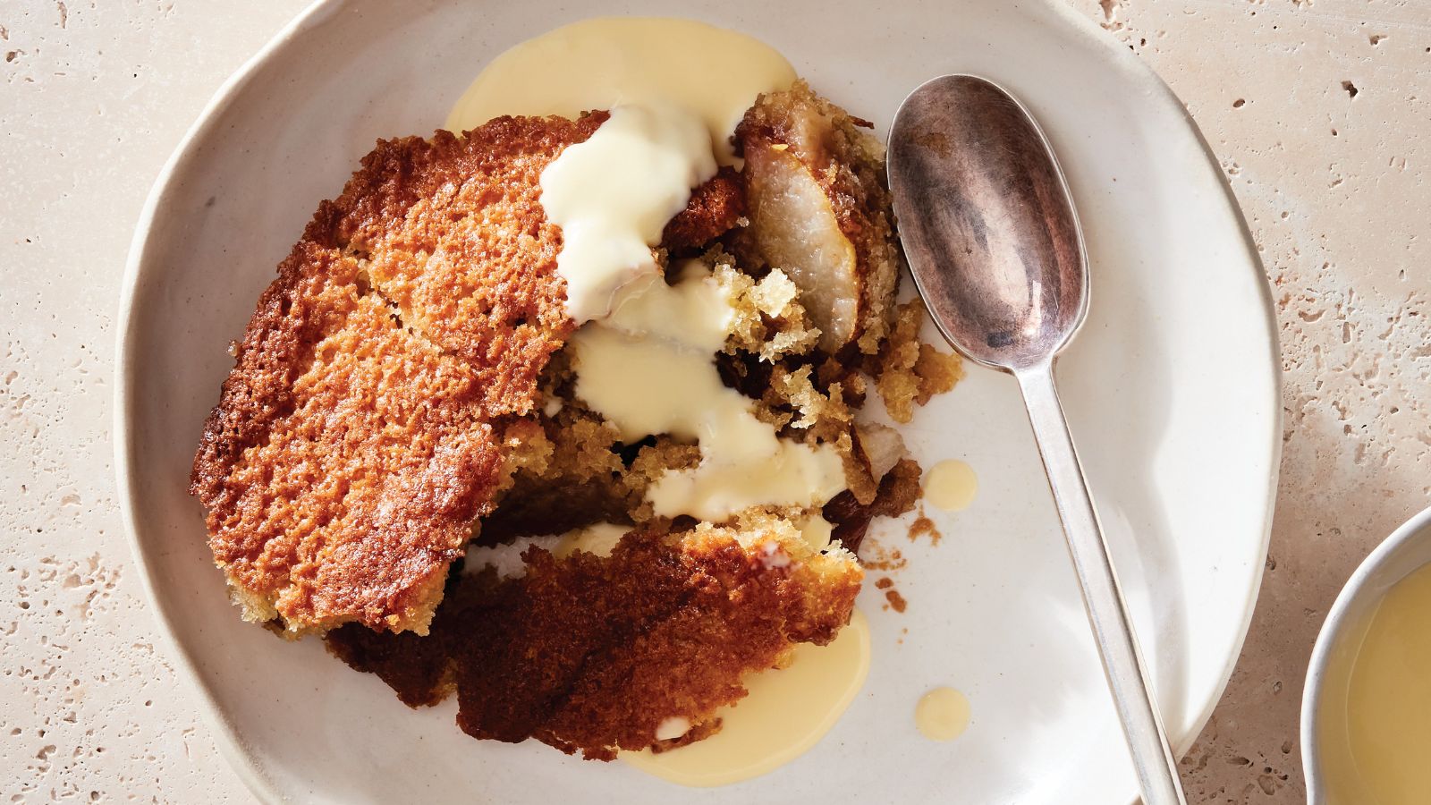 Pear and Caramel Cobbler in a bowl with creme anglais and a spoon