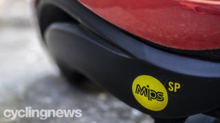 A close up of the yellow circular MIPS logo on a Giro Aether helmet