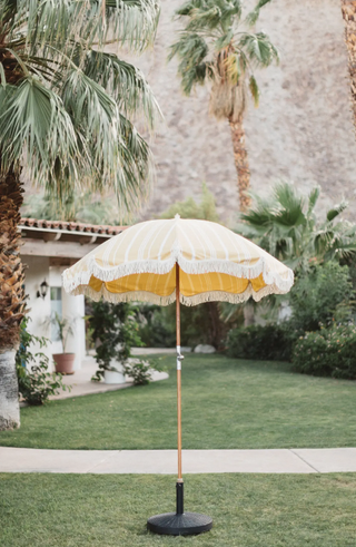 yellow fringed beach umbrella standing in a tropical garden