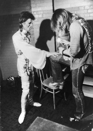 Make-up artist Pierre La Roche prepares English singer David Bowie for a performance as Aladdin Sane, 1973. Bowie is wearing a costume by Japanese designer Kansai