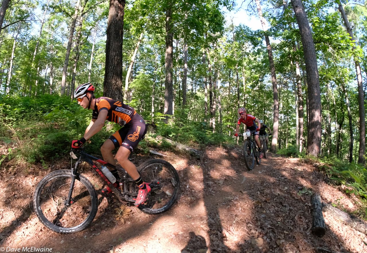 Payson McElveen (Orange Seal-Ridebiker) riding twisty singletrack ahead of Alex Wild.