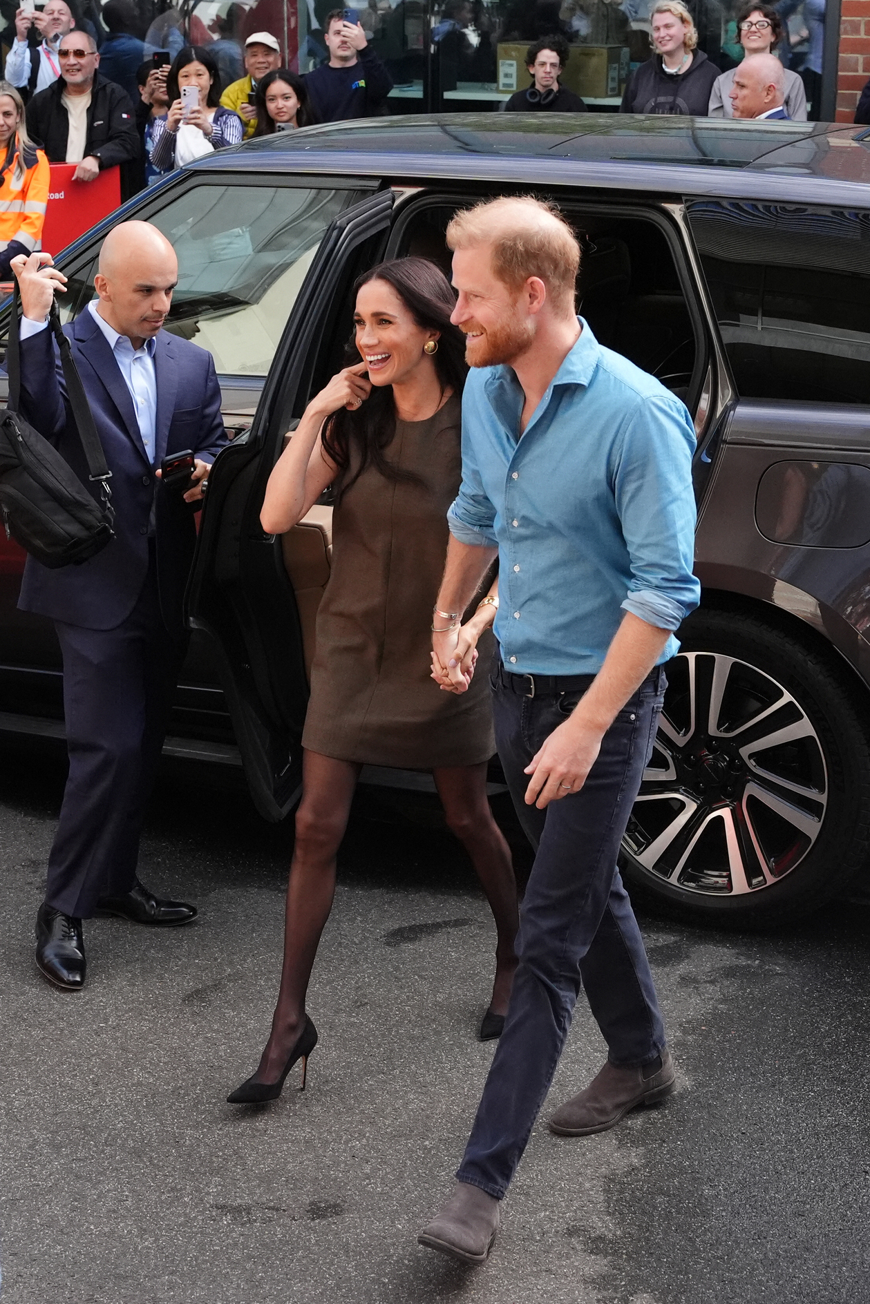 Meghan Markle wearing a short dress walking next to Prince Harry