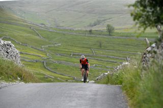 Male cyclist riding out the saddle up a hill