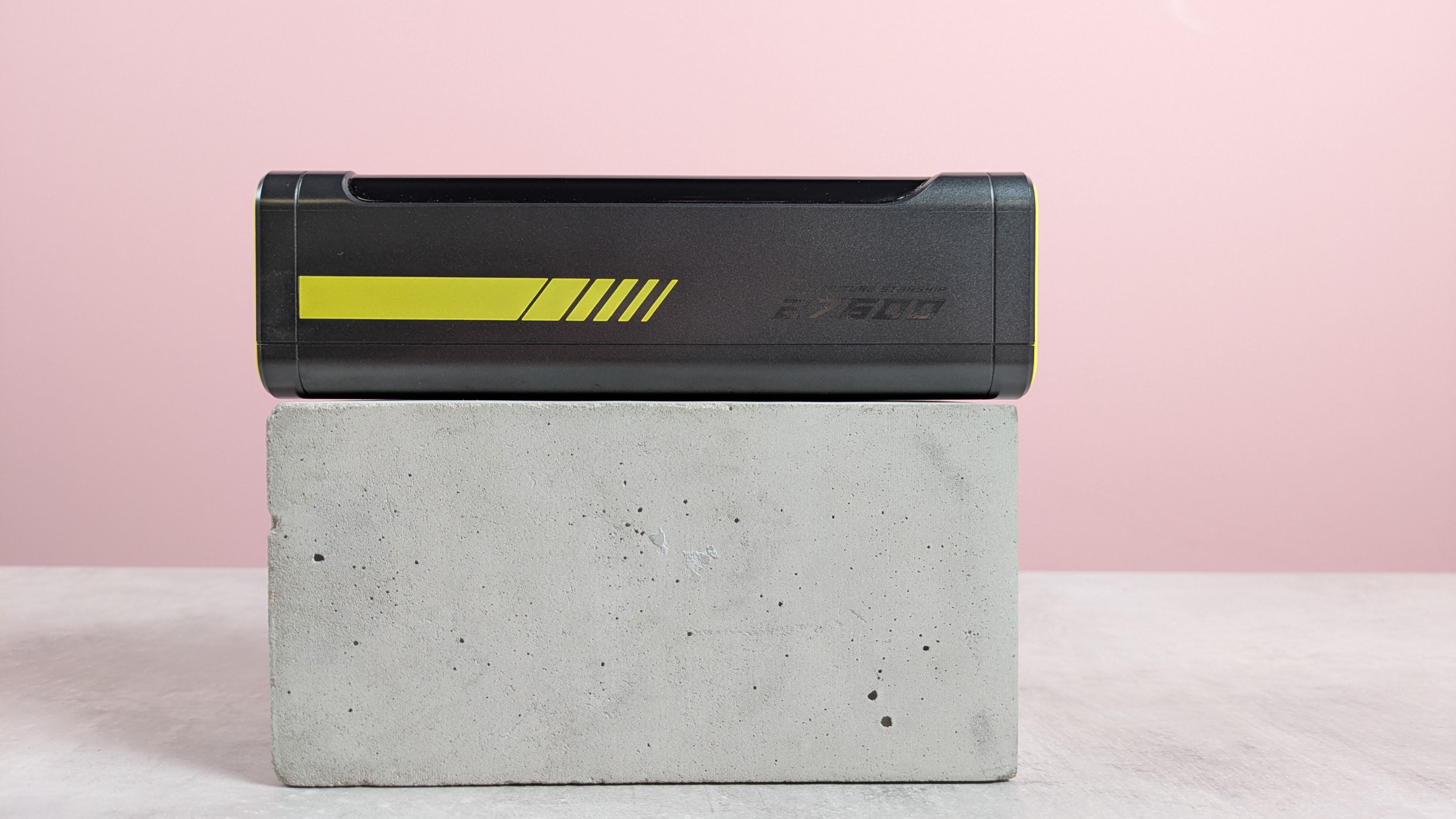 Side view of AOHI Future Starship power bank, on plinth on desk with pink background