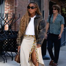 a woman at new york fashion week wearing a statement midi skirt white tshirt and leather jacket