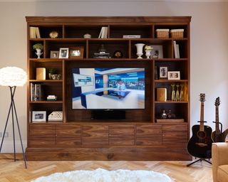 Walnut media unit showing a lamp and guitars eitherside of a large TV