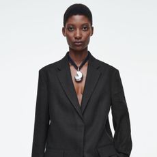 a model wears a black blazer and a silver pendant necklace 