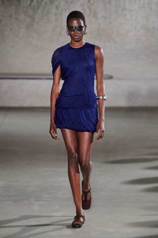 Model wearing a semi-sheer draped minidress on the runway at Tory Burch's spring/summer 2024 show during New York Fashion Week.