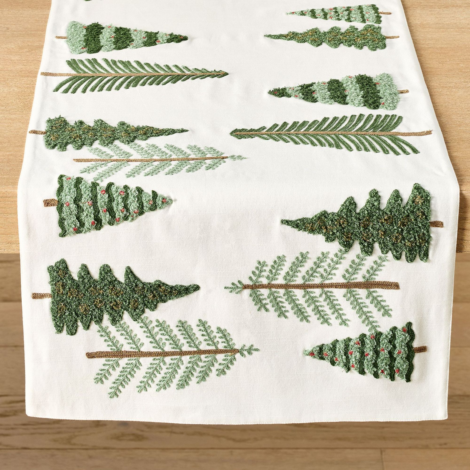 White table runner with green embroidered Christmas trees