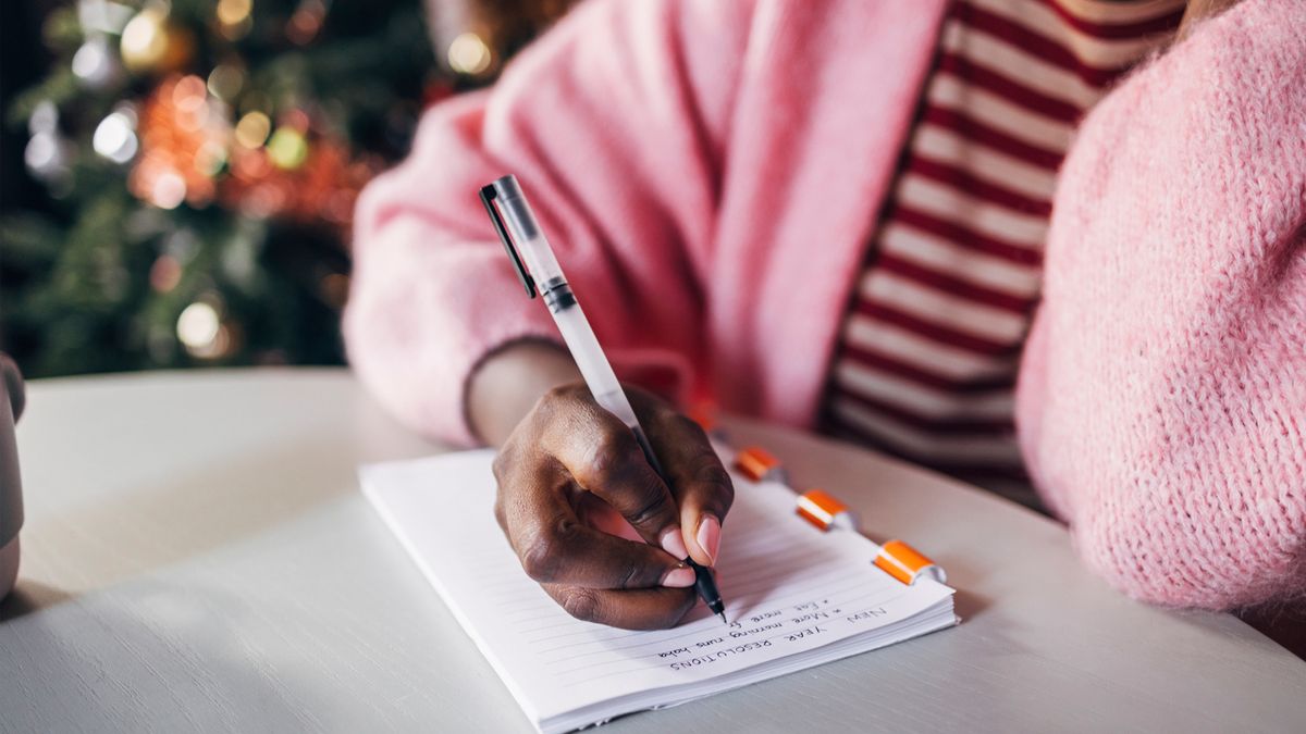 woman writing down her new year&#039;s resolutions