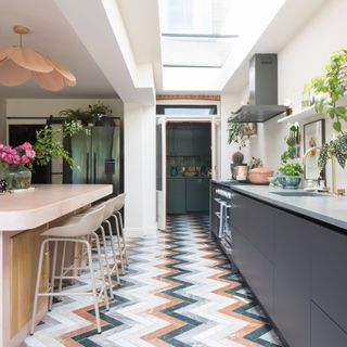 kitchen extension with colourful marble chevron flooring and pink concrete island and dark blue cabinetry