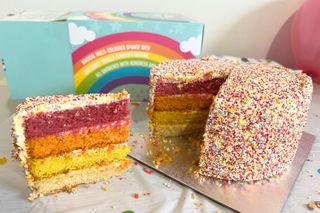 A close up of The BAKERY at ASDA Rainbow Jazzie Cake sliced with rainbow layers