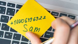 Contact details on sticky note stuck to laptop