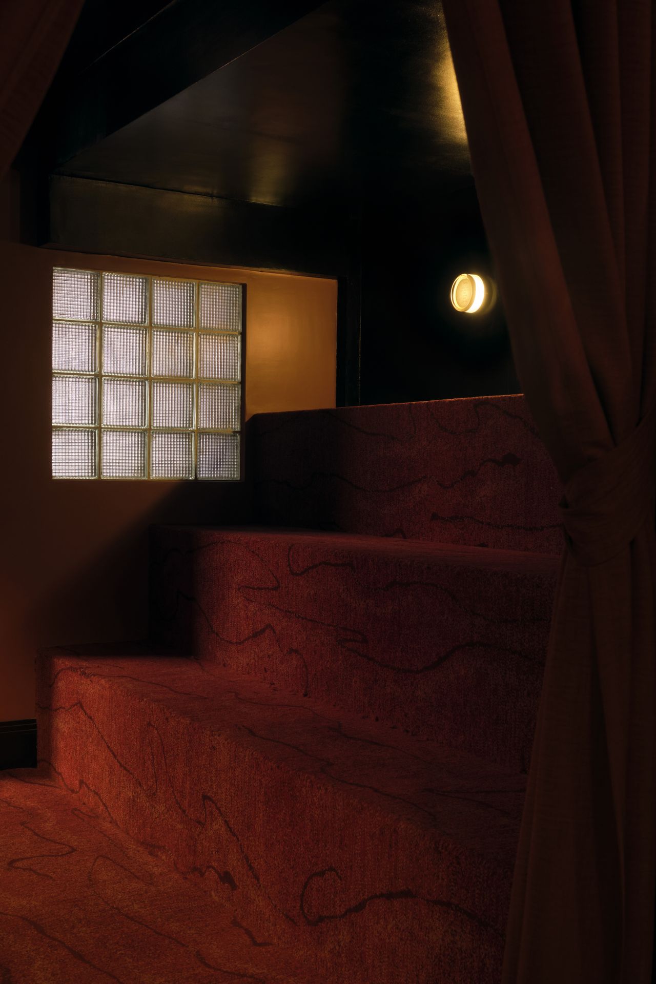 A golden-hued, dimly lit nightclub features velvety red or ochre plush fabrics, reflective surfaces, Art Deco-inspired sconces, and an air of mystery.