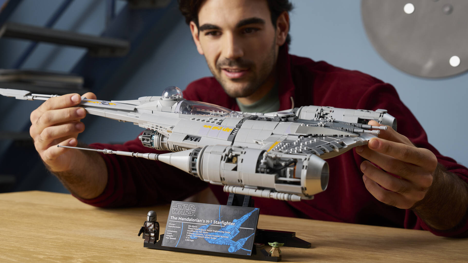 A man smiles while holding the Lego The Mandalorian's N1 Starfighter