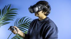 A person wearing the DJI Goggles N3 FPV headset in a dary gray colorway and holding a DJI RC Motion 3 controller