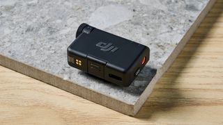 The DJI Mic Mini in black on a stone surface.