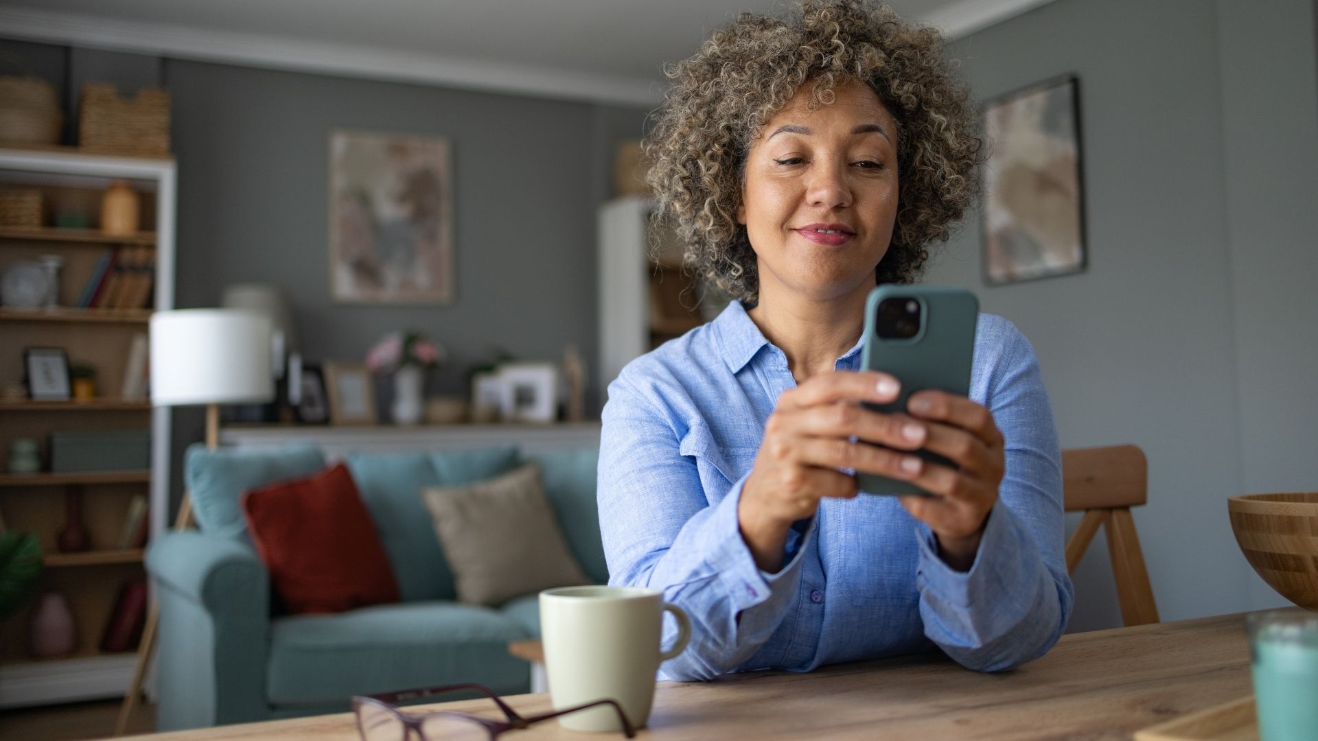 Smiling woman using smart phone at home