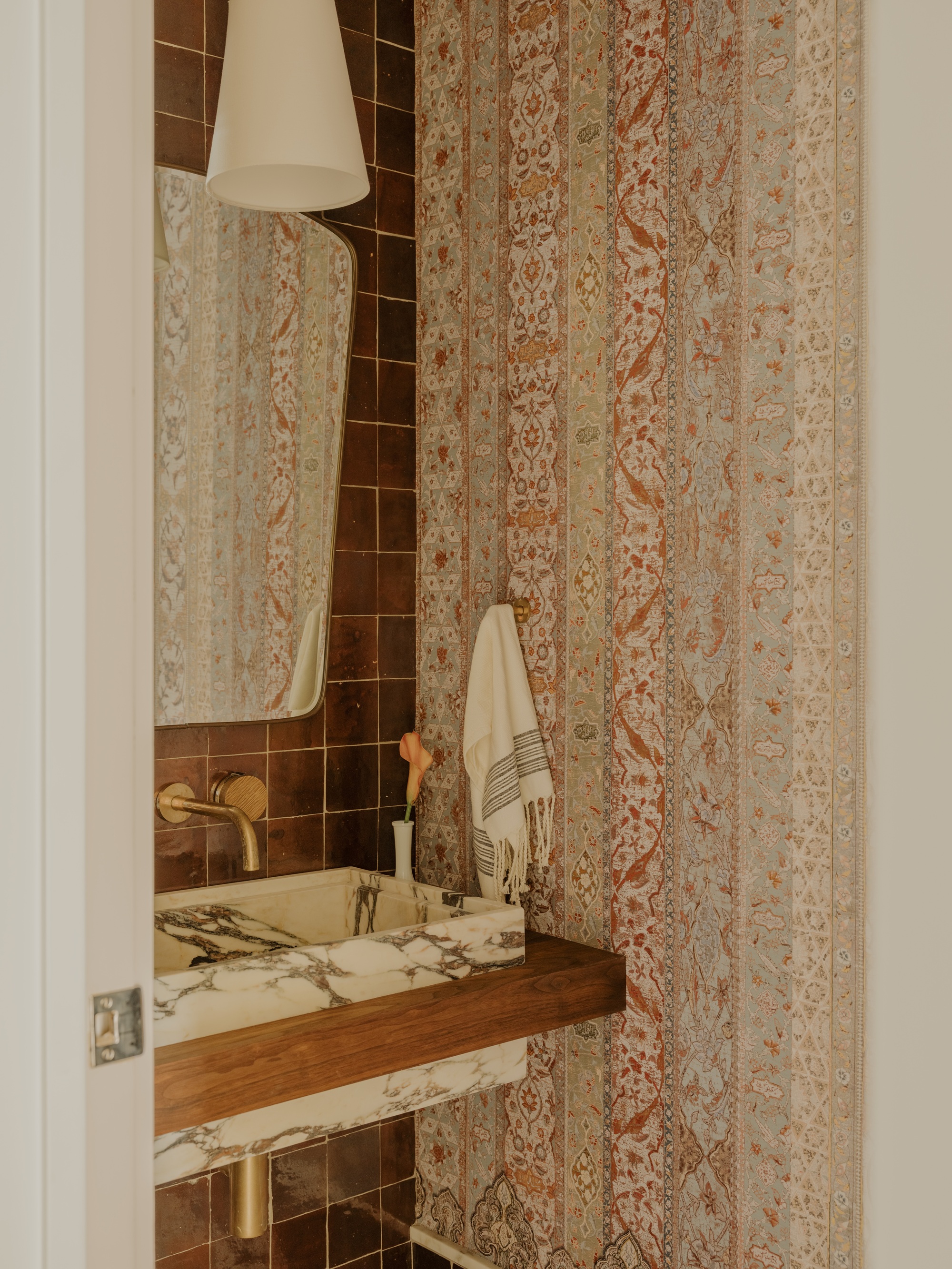 a bathroom with a terracotta patterned wall, with terracotta color tiles