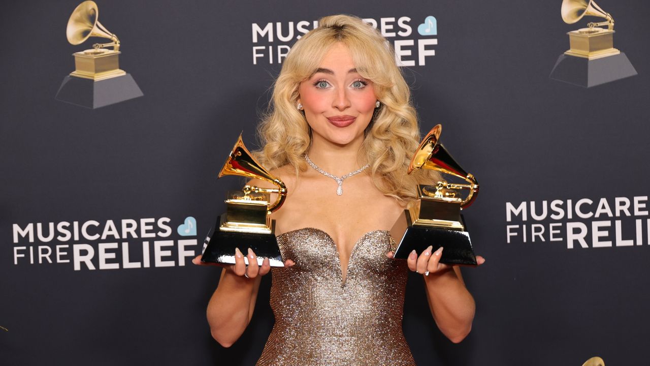 Sabrina Carpenter posing with two gramophone trophies at the Grammys