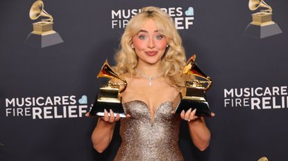 Sabrina Carpenter posing with two gramophone trophies at the Grammys