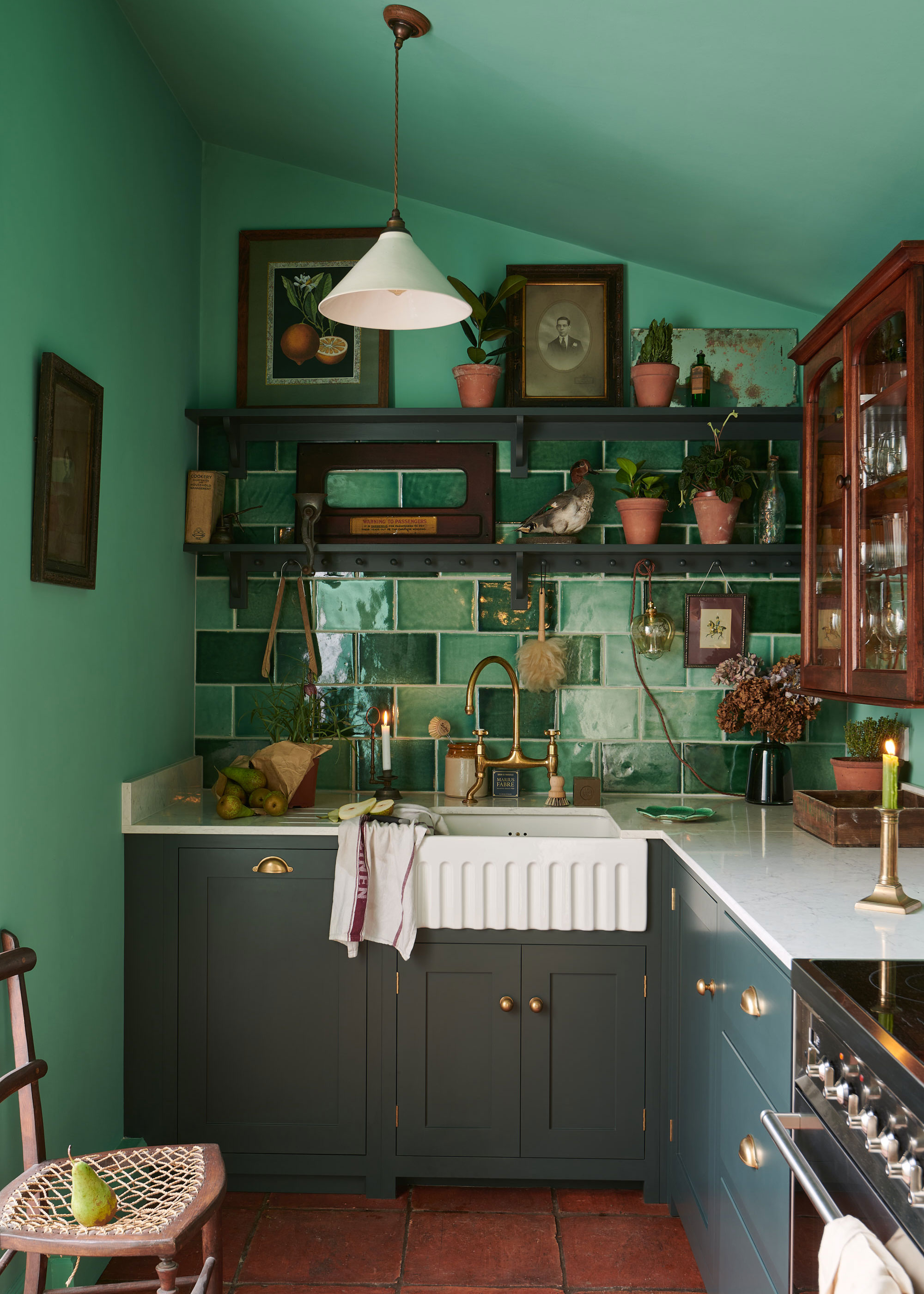 small dark green kitchen with green wall tiles and open wall shelves