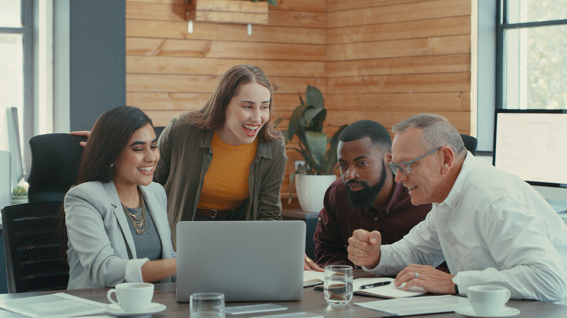 Work colleagues around a desk looking at laptop screen