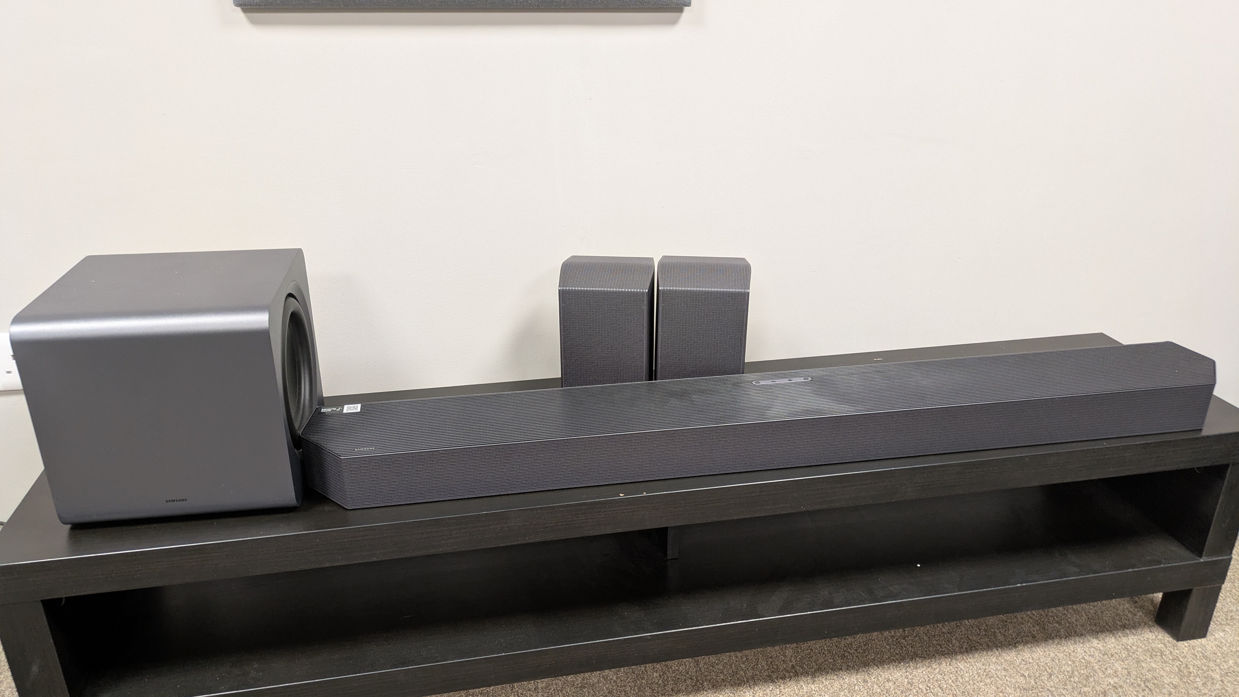 Samsung HW-Q990H system with soundbar, subwoofer and rear speakers on dark wood bench