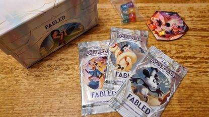 Disney Lorcana Fabled box, boosters, dice, and dial on a wooden surface