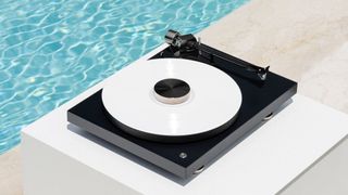 A Pro-Ject Debut Pro turntable outside, beside a swimming pool in the sun