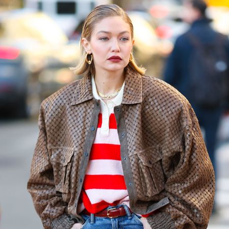 Gigi Hadid wears a brown jacket and a striped shirt 