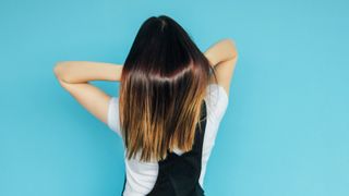 Rear View Of Woman With Long Dyed Hair Standing Against Blue Background - stock photo Photo taken in Yekaterinburg, Russia