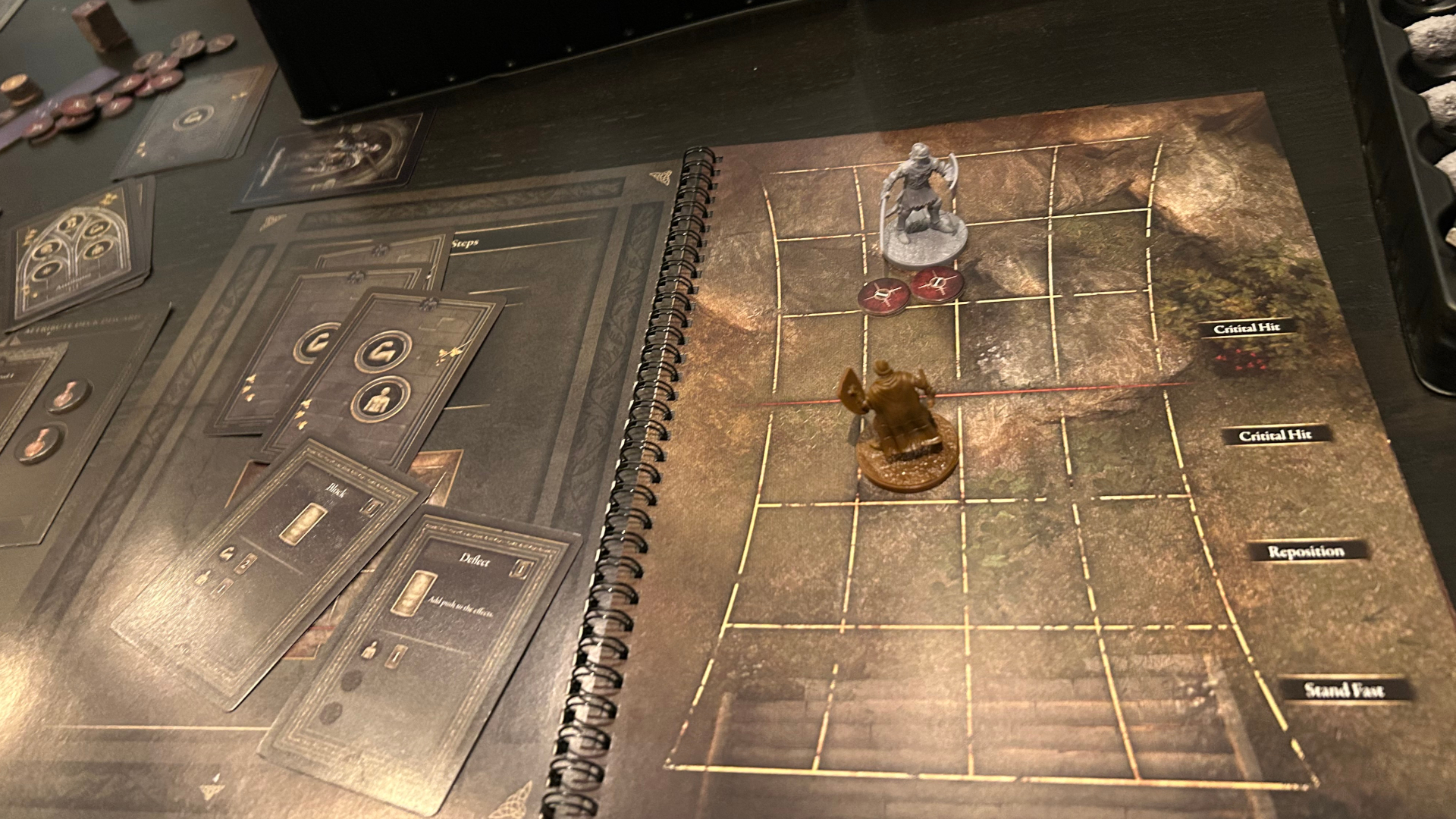 Two Elden Ring miniatures laid out on a gridded book, with cards strewn about the shot