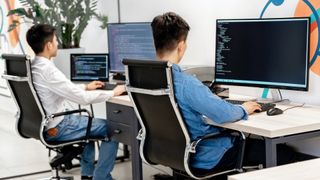 two men sat at desks working on computers