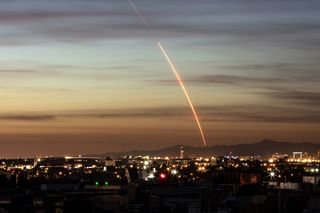 The SpaceX Falcon 9 rocket arcs over city lights of Southern California in this long-exposure of the launch of 10 Iridium Next satellites from Vandenberg Air Force Base on Dec. 22, 2017.