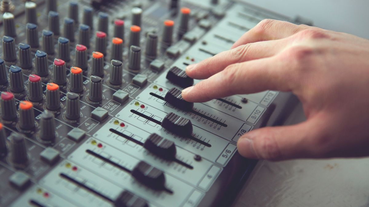 A man pushes a fader on an analogue mixer