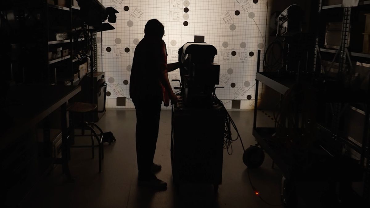 A camerman stands in the dark with an IMAX camera.