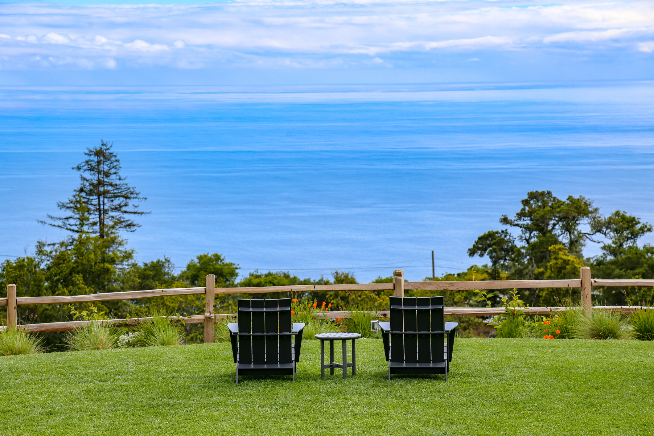 View of the Pacific Ocean on the California coast with two Adirondack chairs and a small table