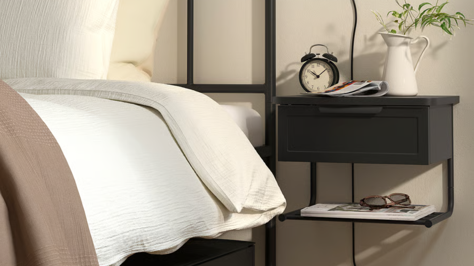 a black wall mounted nightstand next to a bed from IKEA