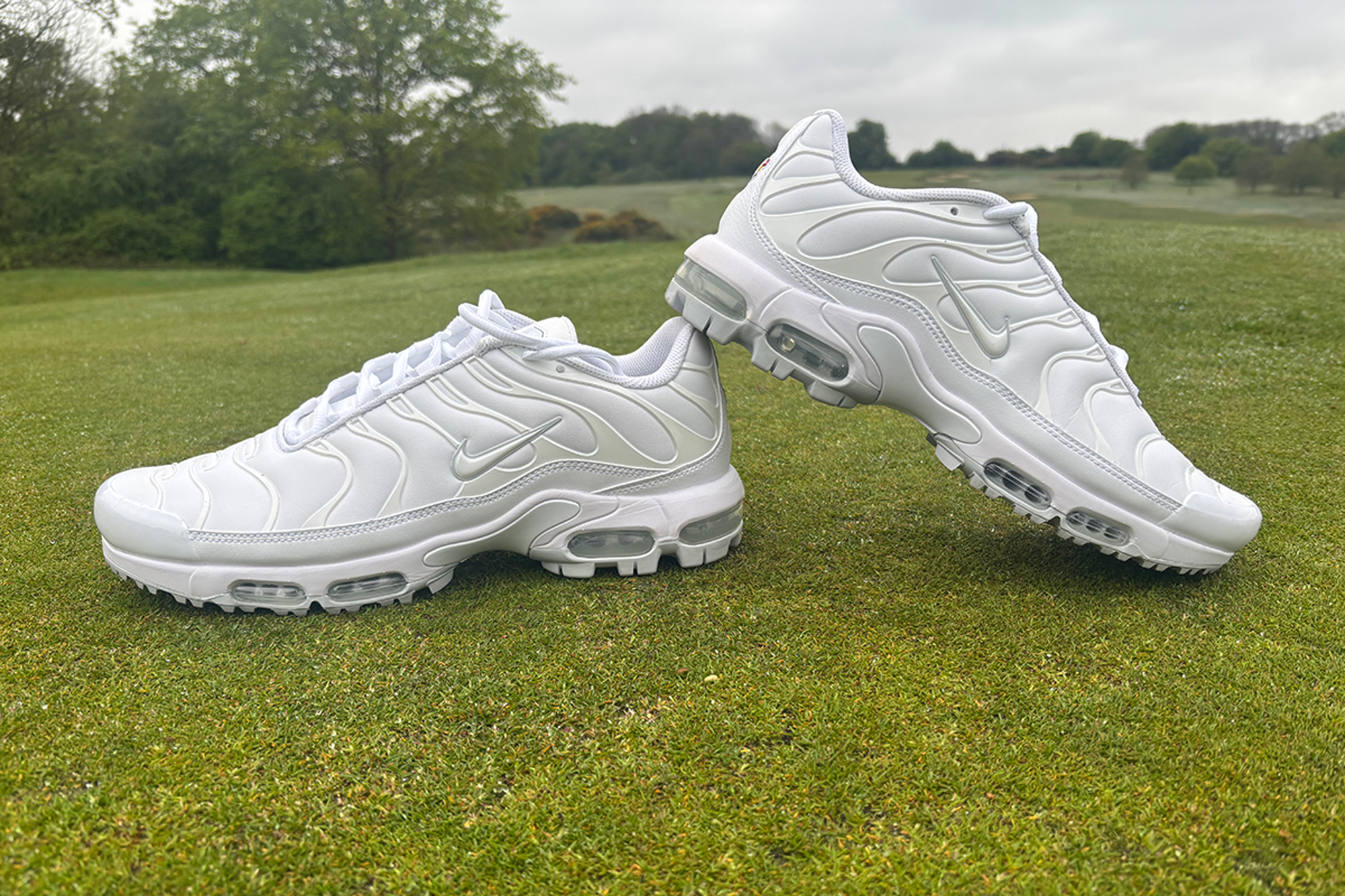 Nike Air Max Plus G Golf Shoes positioned with the left trainer on top of the right trainer on the putting green at Caversham Golf Club