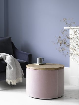 small living room with purple walls and pink pouffe