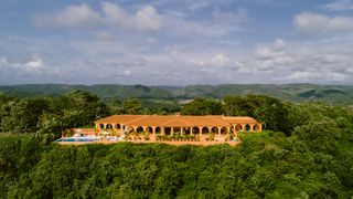 a long and low villa with lush forest in the background