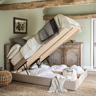 An ottoman bed open in a bedroom to reveal storage space below