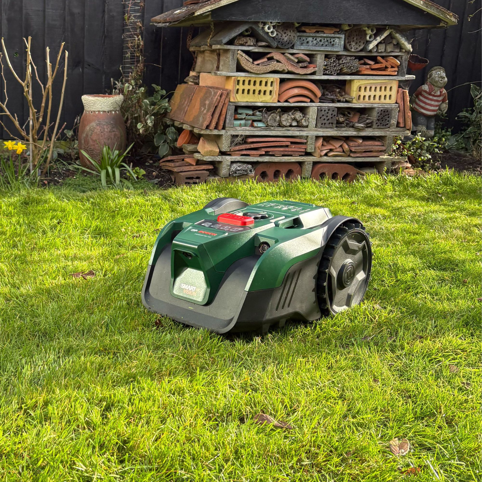 Bosch VISIMOW18V-100 Robot Lawn Mower on grass lawn in front of bug house