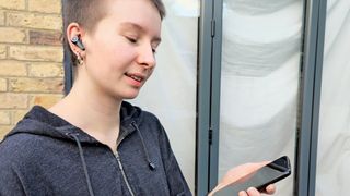 Lypertek PurePlay Z5 earbuds worn by reviewer listening outside with iPhone in hand