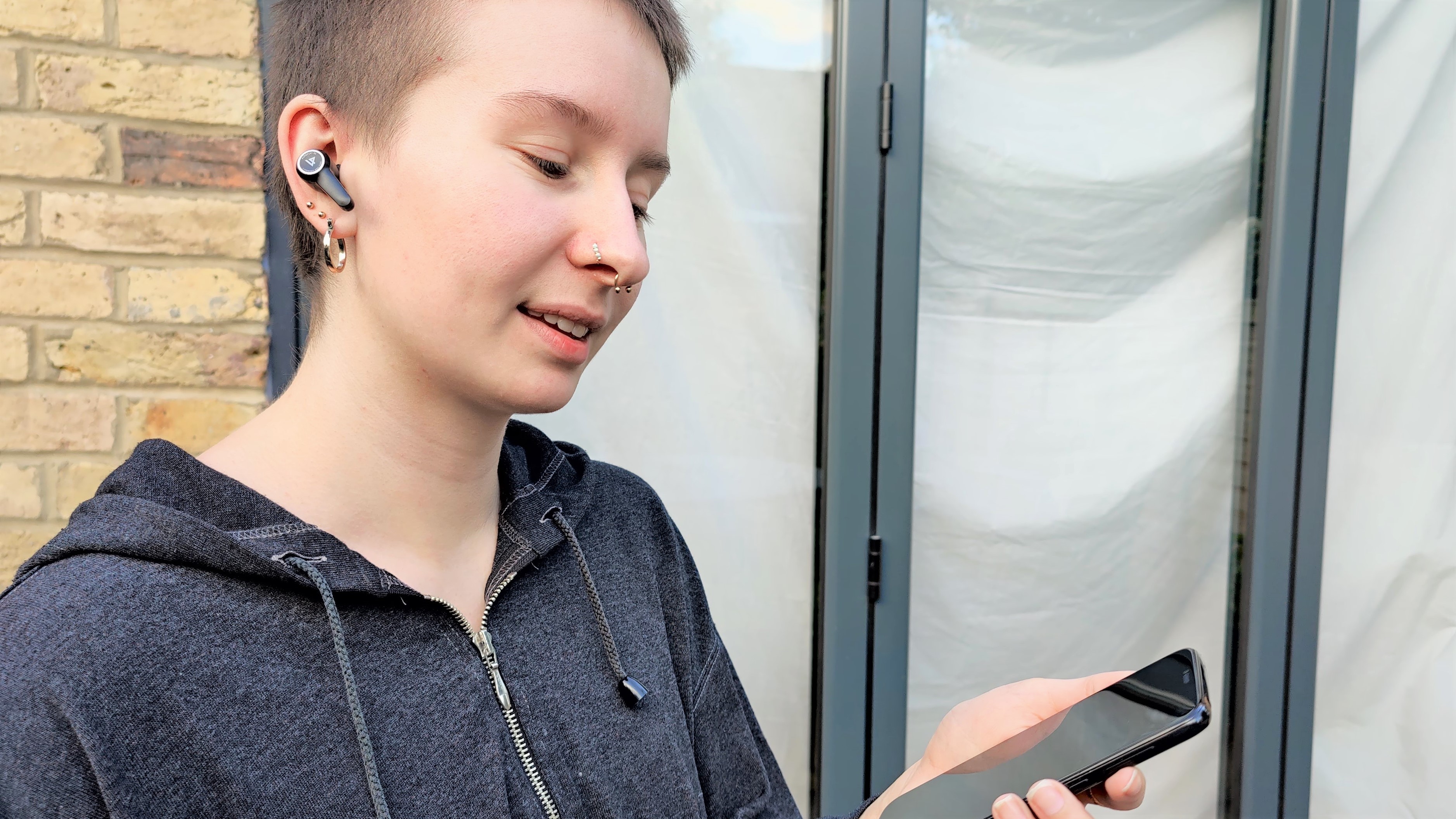 Lypertek PurePlay Z5 earplugs used by reviewers listening outside with iPhone in hand