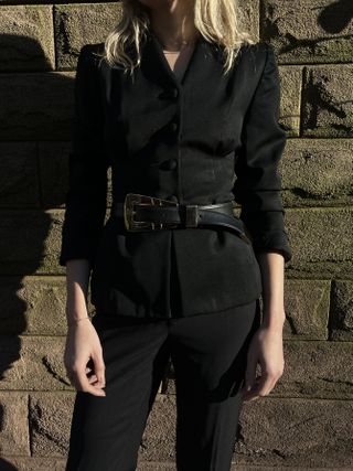 Black blazer with black trousers and a black-and-gold western-inspired belt