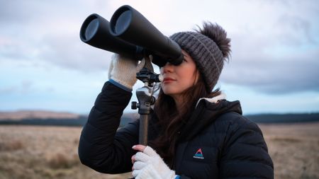 Woman using binoculars to look at the sky