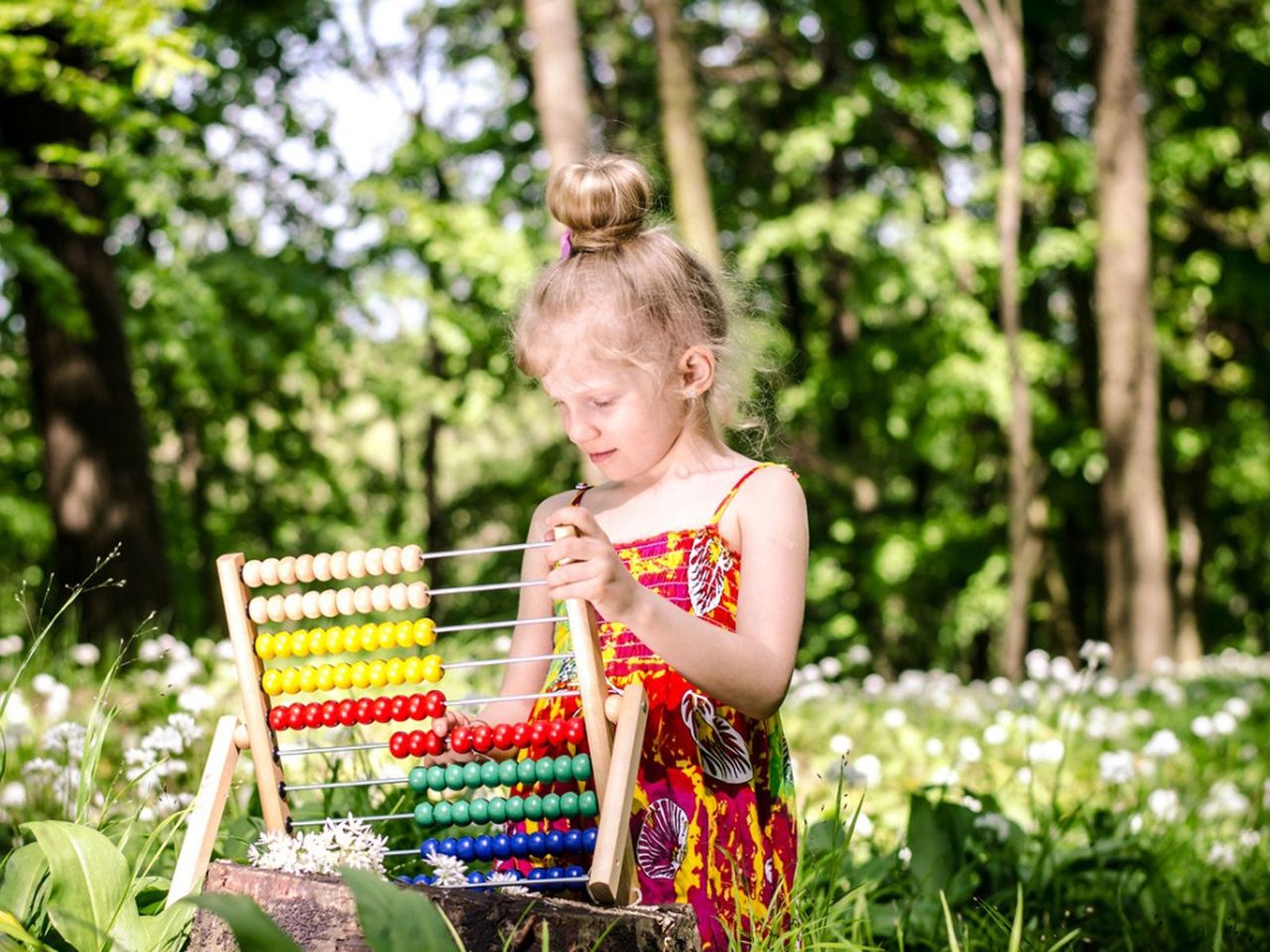 Child Holding An Abacus In A Garden