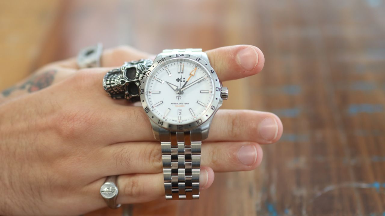 The Christopher Ward Consort bracelet in use on a C63 Sealander GMT, against a wooden background